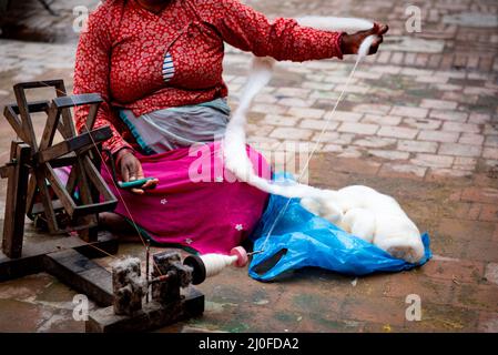 Woman spinning cotton thread on a wooden vintage machine. Kathmandu Nepal Stock Photo
