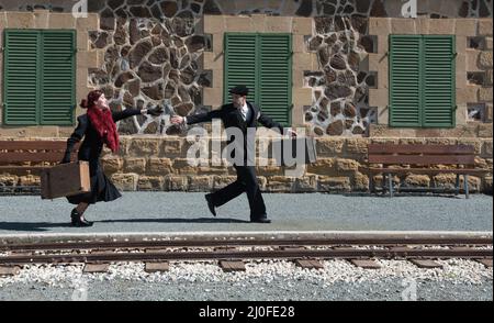 Young couple with vintage suitcase on the trainlines ready for a journey. Stock Photo