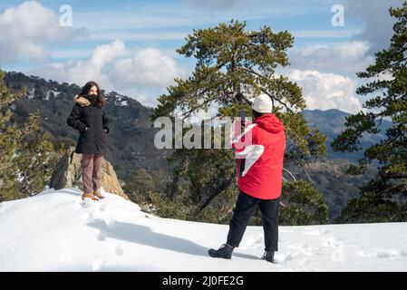 Two young happy teenage taking photos with a mobile phone on a snowy mountain. Stock Photo
