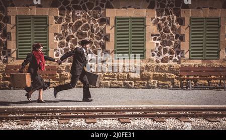 Young couple with vintage suitcase on the trainlines ready for a journey. Stock Photo