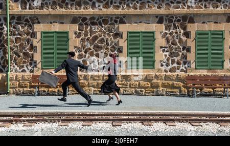 Young couple with vintage suitcase on the trainlines ready for a journey. Stock Photo