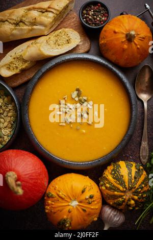 Homemade vegetarian pumpkin cream soup served in ceramic bowl. Decorated with seeds Stock Photo