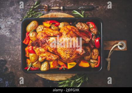Delicious whole chicken cooked with pumpkin, pepper and potatoes. Served in metal baking pan. Stock Photo