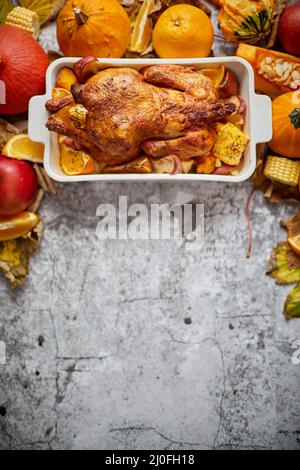 Festive chicken baked by Thanksgiving on white owen plate and a harvest of seasonal vegetables Stock Photo