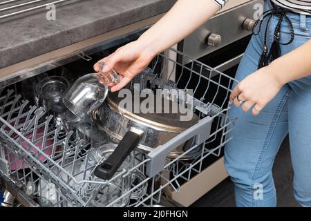 Operation of the dishwasher after the end of the cycle, i.e. removing washed dishes from the device. Stock Photo