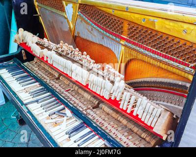 An old broken piano with a missing wall and cover and broken keys Stock Photo