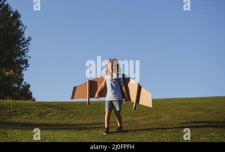 Child boy dreams and travels. Boy with airplane toy outdoors. Happy child playing with toy airplane outdoors in summer field. Travel, vacation and Stock Photo