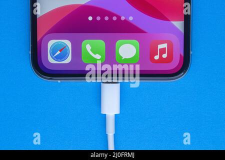 Calgary, Alberta, Canada. Nov. 19, 2020. An iPhone Pro Max charging on a blue background. Stock Photo