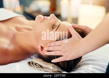 I deserve every minute of it. Shot of a beautiful young woman lying on a massage table at the day spa. Stock Photo