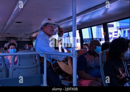 Local resident in San Jose, Costa Rica singing and playing guitar while riding by bus full of tourists Stock Photo