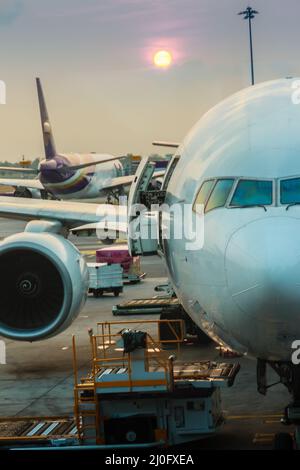 Airplane at the terminal gate ready for takeoff in modern international airport. Beautiful sunrise in the airport with airplane Stock Photo