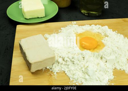 Fresh and raw chicken egg in flour. Bright color of egg yolk and wheat flour. Ingredients for baking on the table. Background with copy space for text Stock Photo