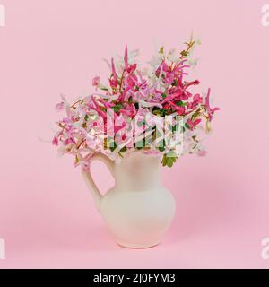 Still life with a bouquet of pink, white and purple red flowers in a white jug on a pink background Stock Photo