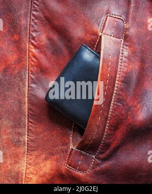 Black wallet sticking out of the pocket of the red jacket made of leather Stock Photo