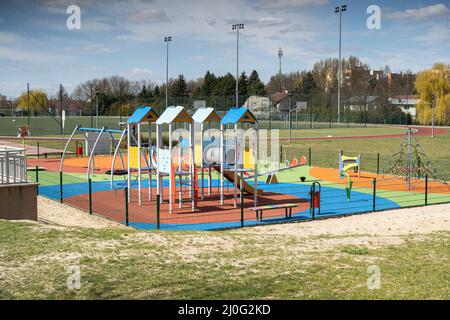 A playground for children to play. Colorful play sets and a safe surface. Coniferous tree branch with cones. Pine. Stock Photo