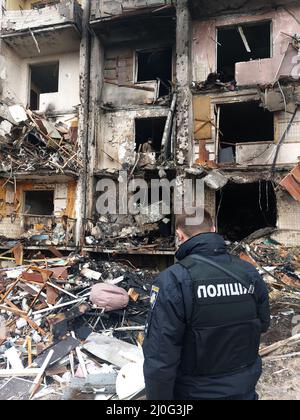 KYIV, UKRAINE 25 FEBRUARY. Ukrainian policeman inspect the damage of a residential building hit by an early morning missile strike at Koshytsa Street on 25 February 2022 in Kiev, Ukraine. Russia began a large scale attack on Ukraine after Russia's parliament approved treaties with two breakaway regions in eastern Ukraine. Stock Photo