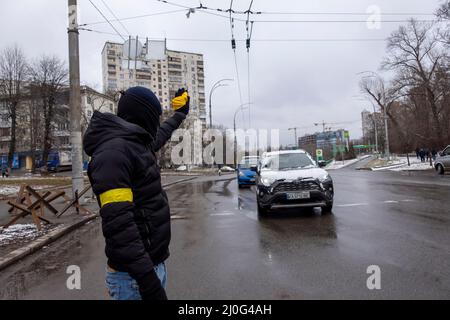 KYIV, UKRAINE 01 March. A member of the Territorial defense forces stops a car in a roadblock in Protasiv Yar neighborhood as Russia's invasion of Ukraine continues on 01 March 2022 in Kiev, Ukraine. Russia began a military invasion of Ukraine after Russia's parliament approved treaties with two breakaway regions in eastern Ukraine. It is the largest military conflict in Europe since World War II. Stock Photo