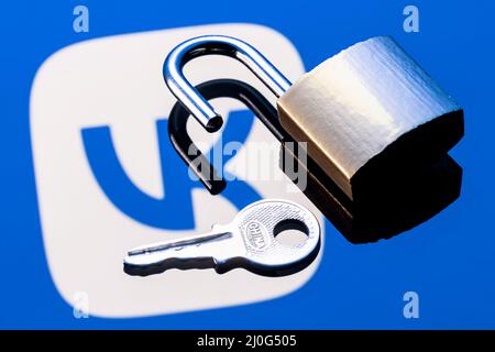An open security lock and key on the background of the VKontakte social network logo in the mirror reflection. Stock Photo