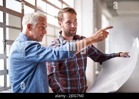 That walll needs to go. Shot of two male architects holding blueprints inspecting a building. Stock Photo