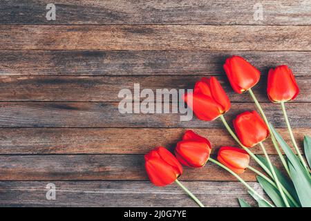 Bouquet of red tulips on wooden retro grunge background with copy space. Mother's Day concept Stock Photo