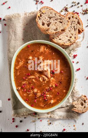 Delicious and homemade tripe soup as traditional soup in Poland. Spicy and aromatic tripe soup seasoned with pepper and served with bread. Stock Photo