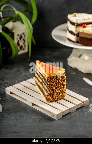Deliciouse cake with chocolate cream, hazelnut and caramel dressing on the miniature wooden pallet. Traditional hungarian Dobos Stock Photo