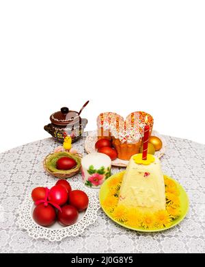 Easter composition with cakes and painted eggs with a yellow chicken in a nest on a table isolated on white background with a co Stock Photo