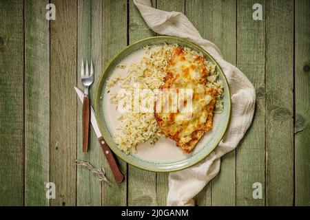 Grilled chicken with ananas and cheese with rice in a green elegant porcelain plate, on the old, green wood table Stock Photo