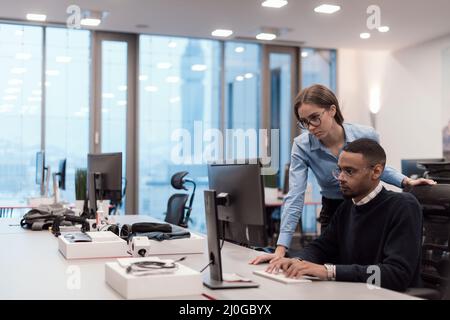 Young smiling woman explaining to serious African American coworker project strategy. Diverse startup coworkers students woman and man talking Stock Photo