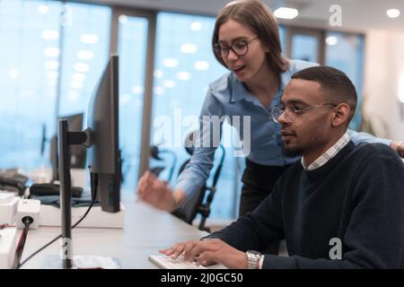 Young smiling woman explaining to serious African American coworker project strategy. Diverse startup coworkers students woman and man talking Stock Photo
