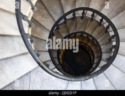 Old spiral staircase with marble steps and wrought iron handrail Stock Photo