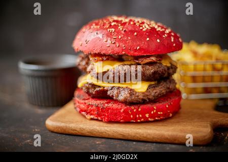 Homemade red sesame bun double bacon cheese burger. Served with french fries on wooden board. Stock Photo