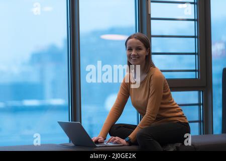 A young woman sitting in a modern space while working on a project on a laptop. Selective focus  Stock Photo