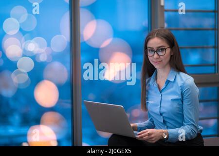 A young woman sitting in a modern space while working on a project on a laptop. Selective focus  Stock Photo