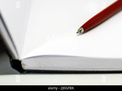 Red ballpoint pen on the blank white pages of an open notebook Stock Photo