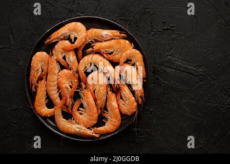 Boiled big sea prawns or shrimps placed on black ceramic plate Stock Photo