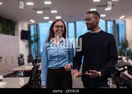 Two happy diverse professional executive business team people woman and African American man walking in coworking office. Multicultural company Stock Photo