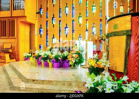 Pulpit with flowers and the front part of the temple seen in the Annunciation of the Blessed Virgin Mary Catholic Church. There are stained glass skyl Stock Photo