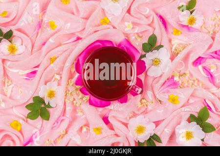 A cup of tea on a background of pink fabric in pink rose flowers Stock Photo