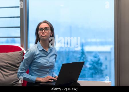 A young woman sitting in a modern space while working on a project on a laptop. Selective focus  Stock Photo