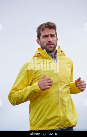 Keep heading towards your goals. Low angle shot of a handsome young man running in rainy weather. Stock Photo