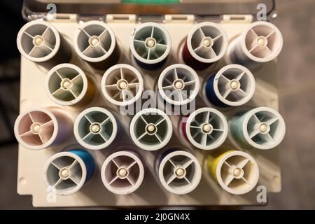 many different colors of thread organized on spools in a storage case Stock Photo