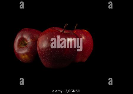 Three juicy red apples on a black background. Stock Photo