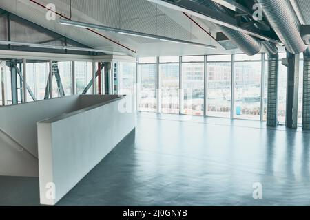 Ready for business. Shot of an empty office covered with widows and with a staircase leading to a bottom area. Stock Photo