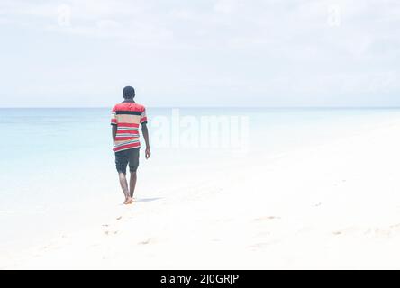 Black African young man walking on tropical beach Stock Photo