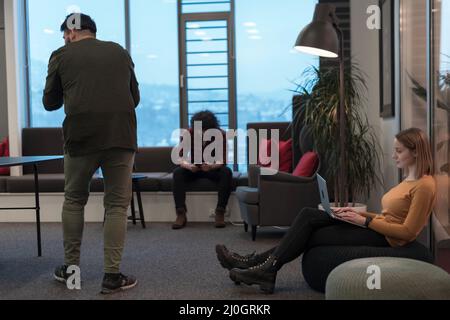 Two business women sitingt in a modern coworking space on a break from work and relax using a laptop. Selective focus  Stock Photo
