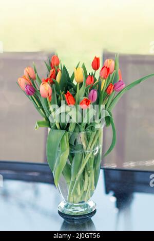 Beautiful flowers bouquet in vase on the glass table. Stock Photo
