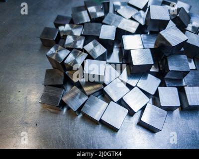 pile of small machined shiny steel cubes on metal surface Stock Photo