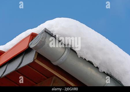 Roof with snow on a sunny day with blue sky as background Stock Photo