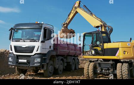 Excavator loads trucks with excavation Stock Photo